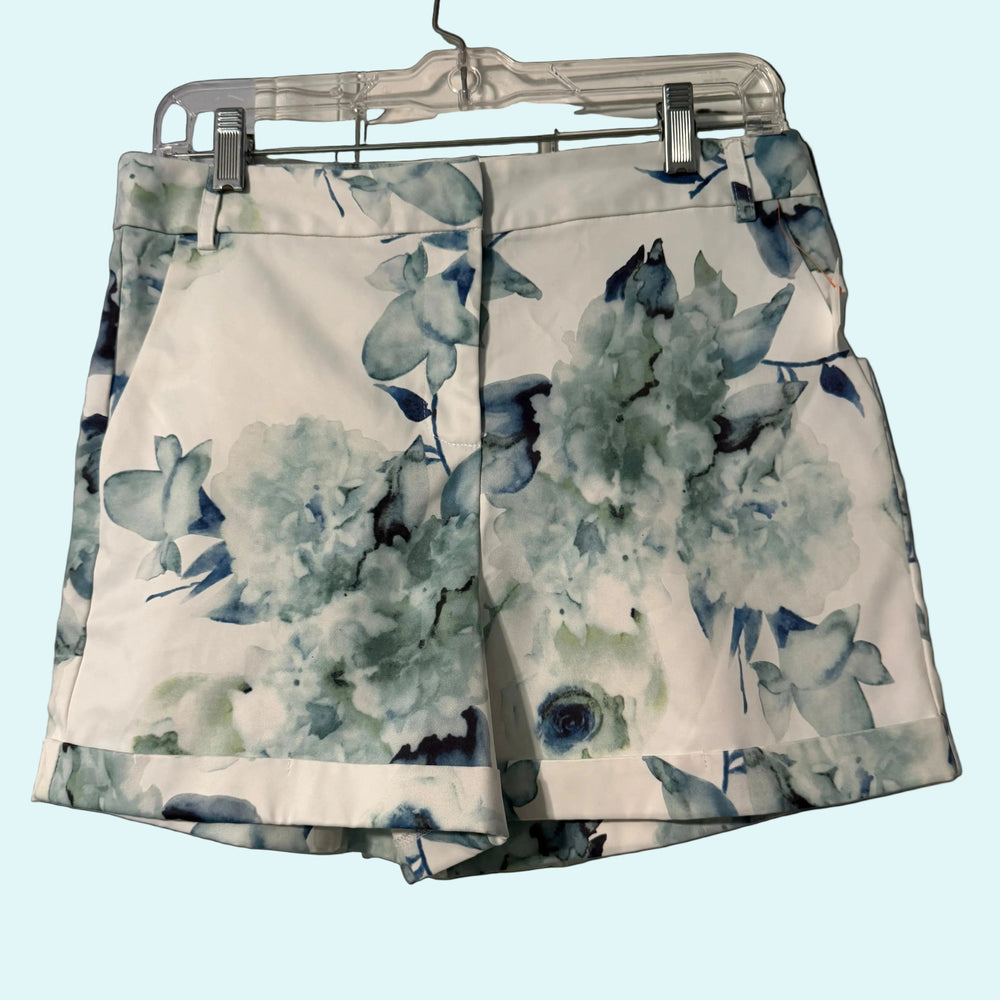 Floral patterned shorts on a hanger against a neutral background
