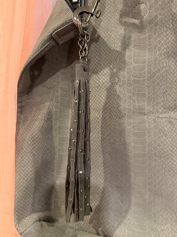 Close-up of studded tassel and snake-effect texture on grey bag